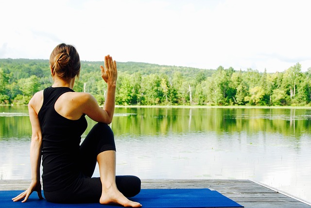 Entspannung: Frau sitzt am See und macht Yoga